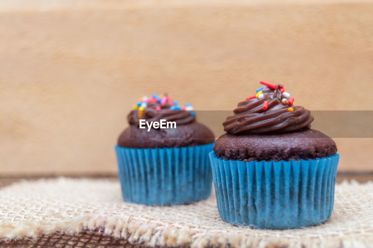 CLOSE-UP OF CUPCAKES ON TABLE AGAINST WALL