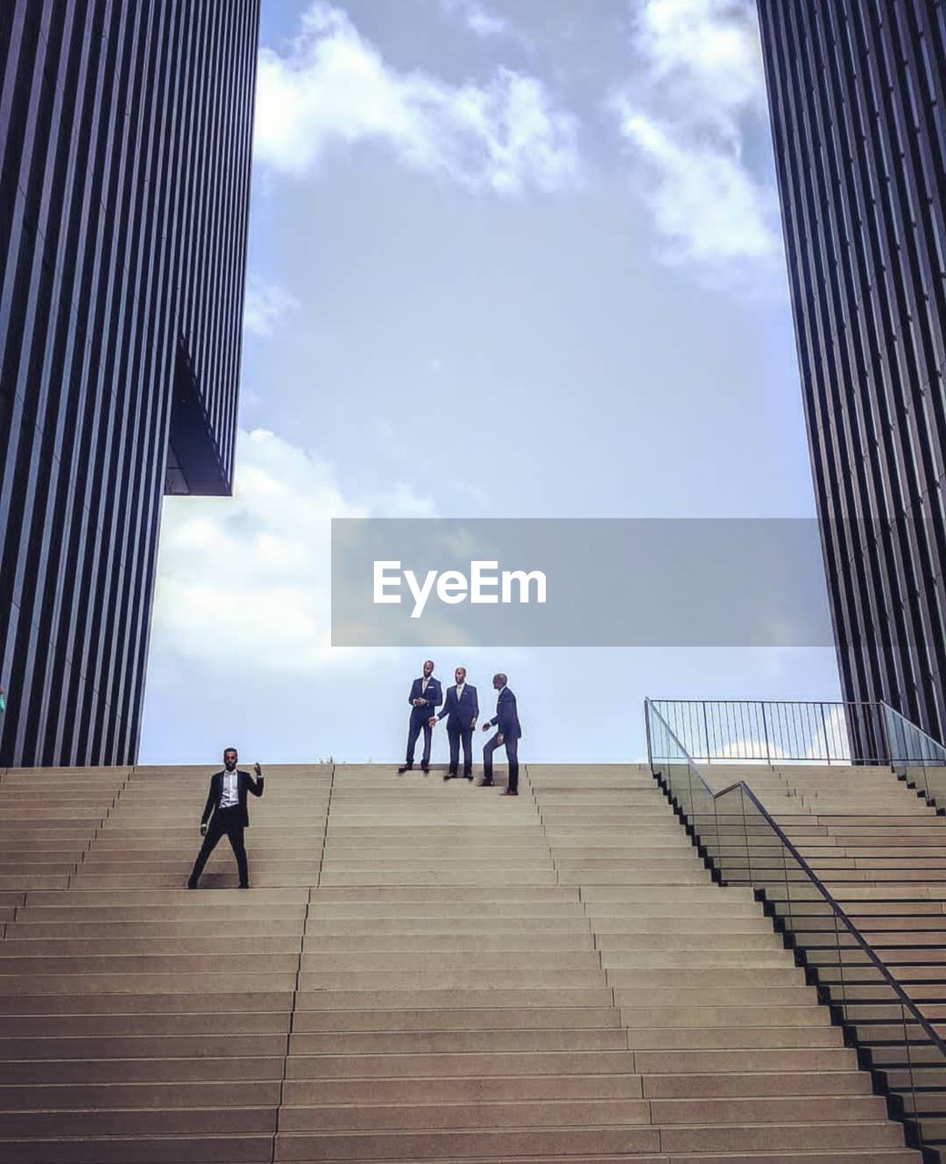 Businessman gesturing while colleagues standing in background in city