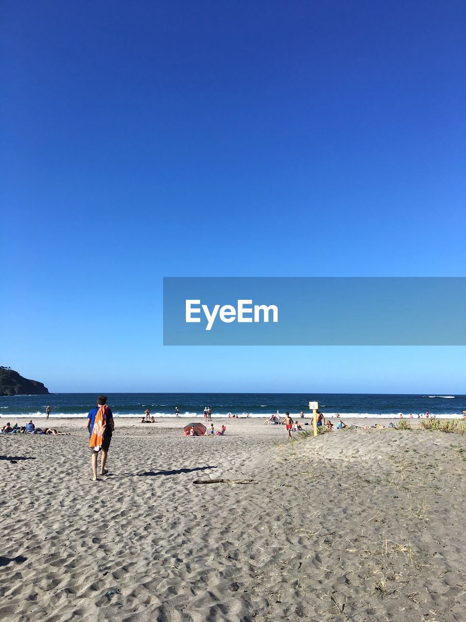 People on beach against clear blue sky