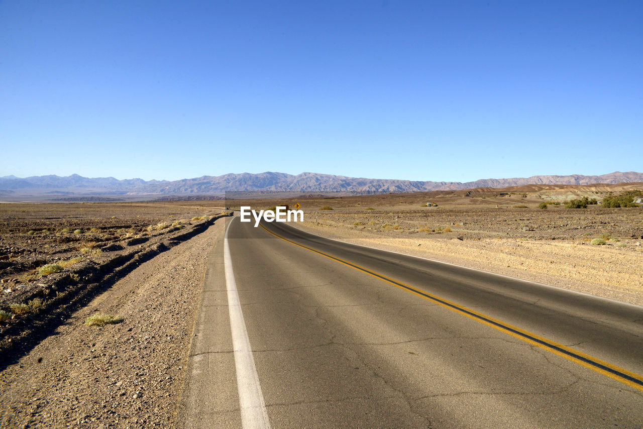 Empty road along landscape against clear sky