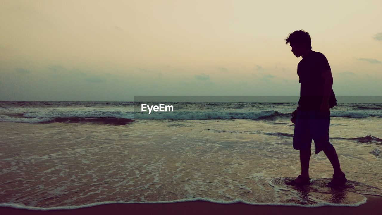 Full length of young man standing on shore at beach