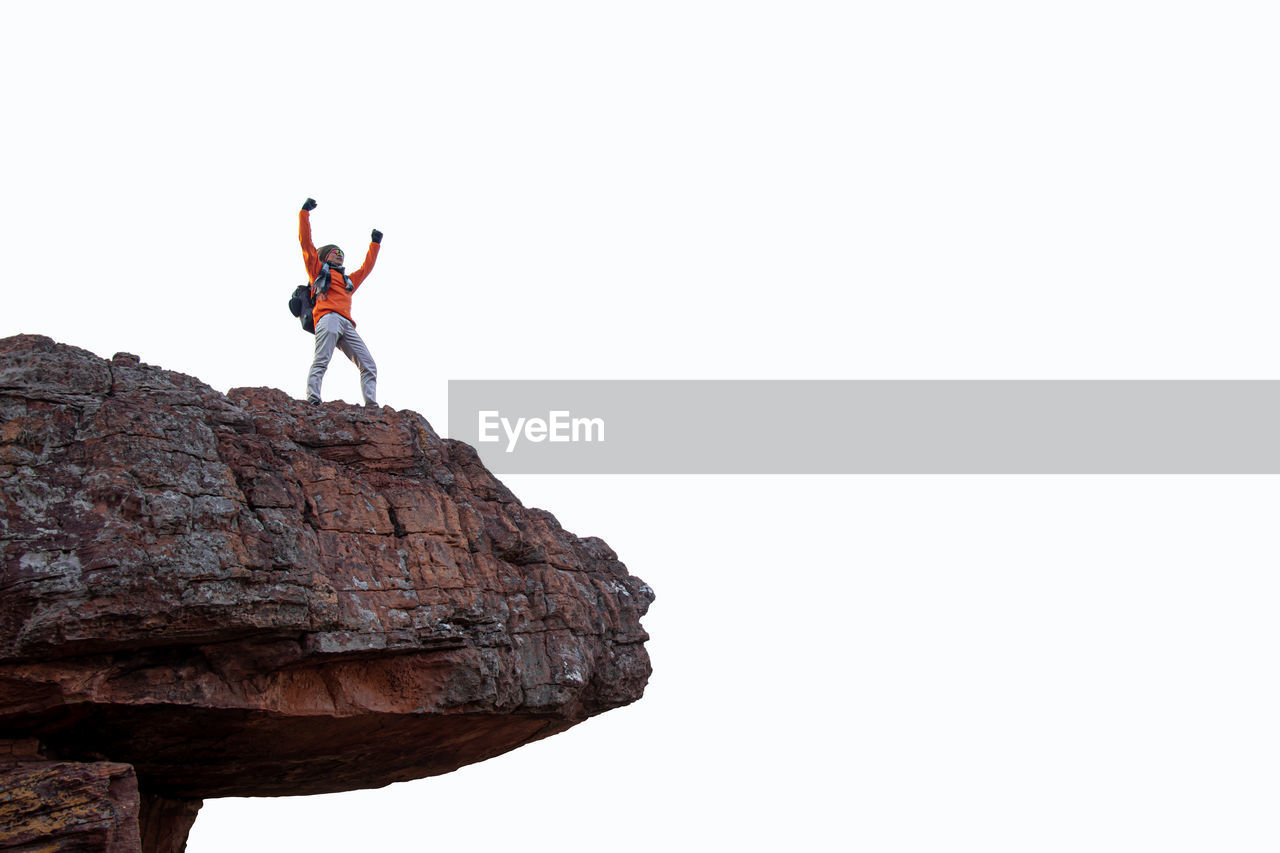 low angle view of man standing on rock against clear sky