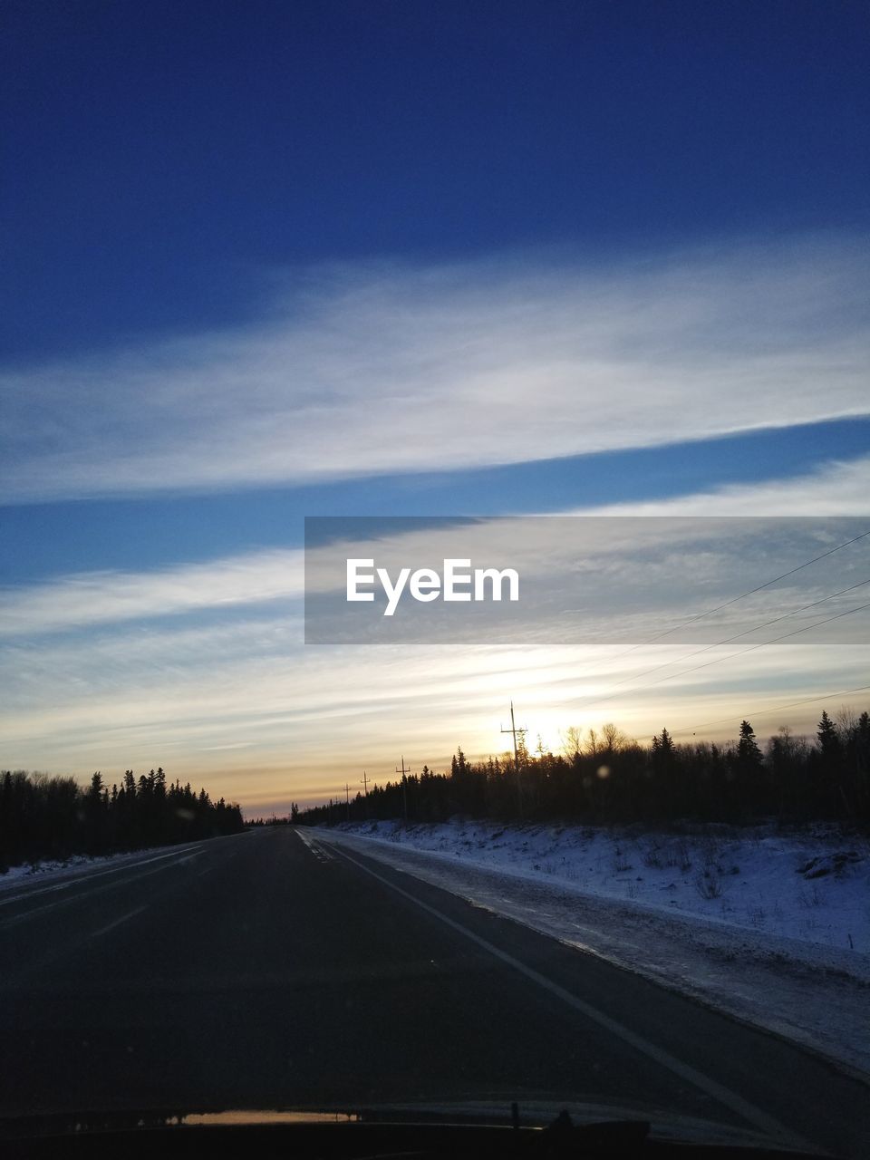 ROAD AGAINST SKY SEEN THROUGH CAR WINDSHIELD