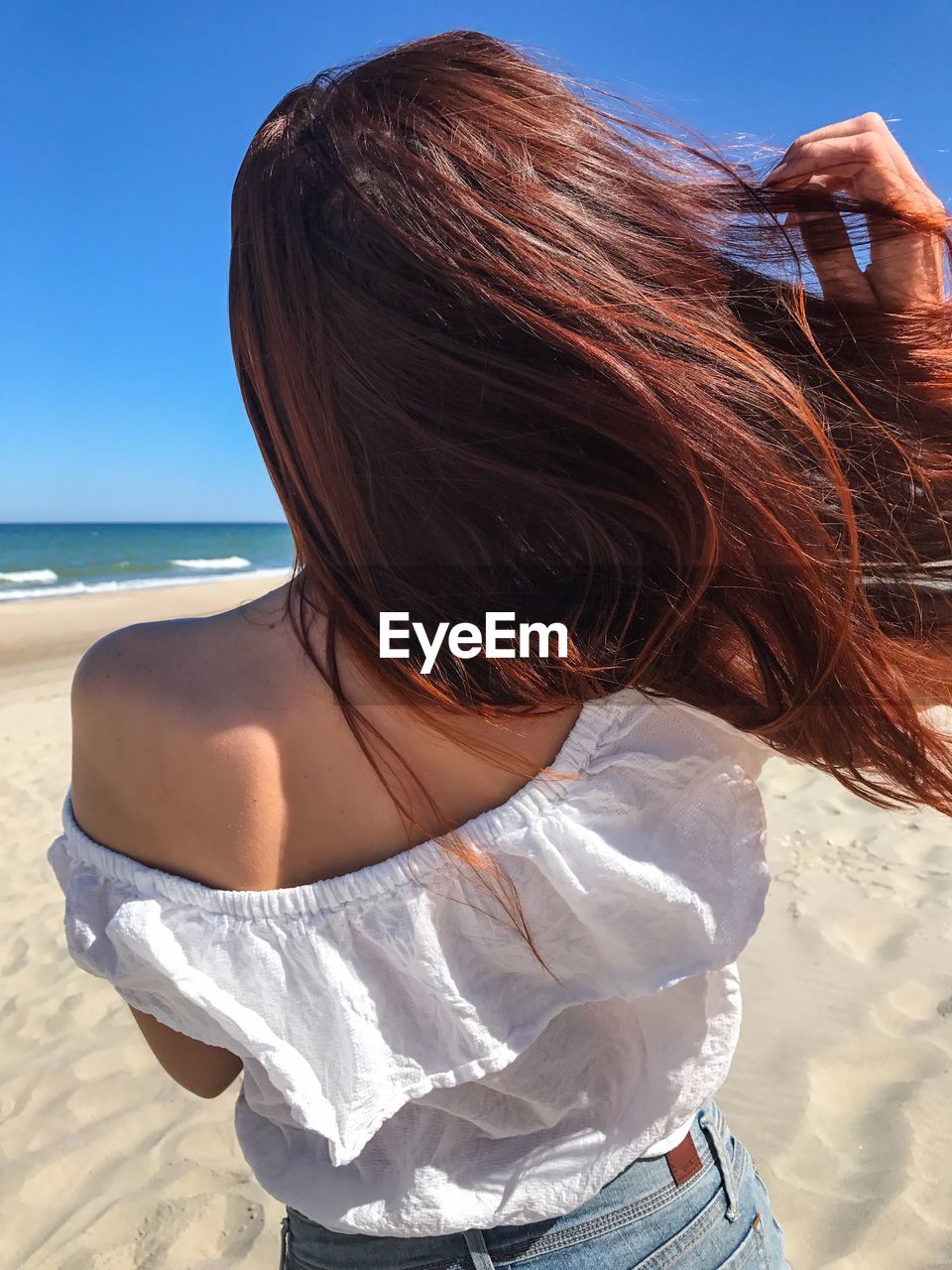 Rear view of woman with tousled hair at beach