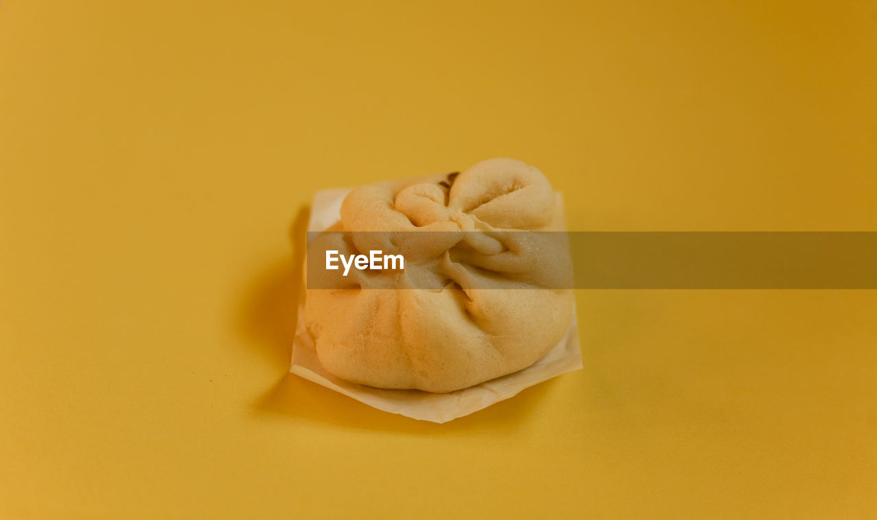 Close-up of meatbun or bakpao on yellow background