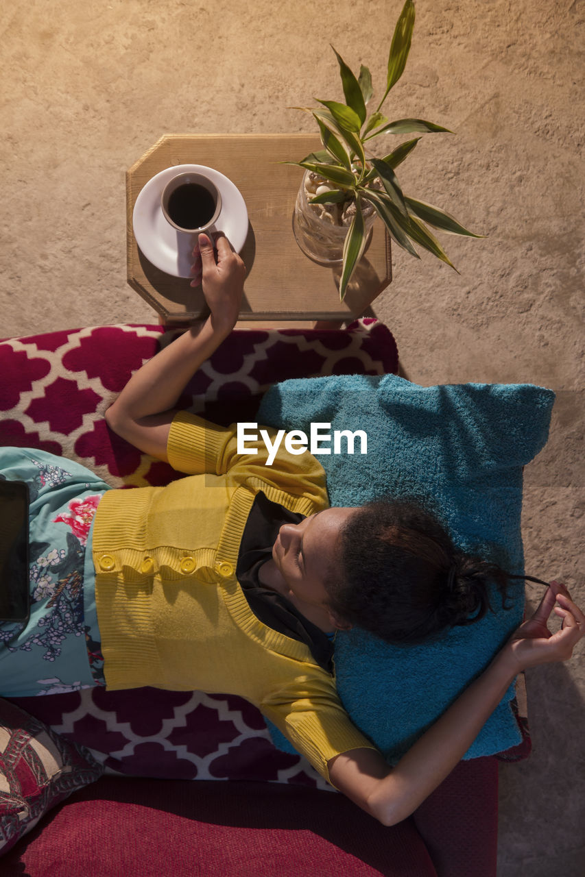 High angle view of woman using digital tablet while lying on sofa