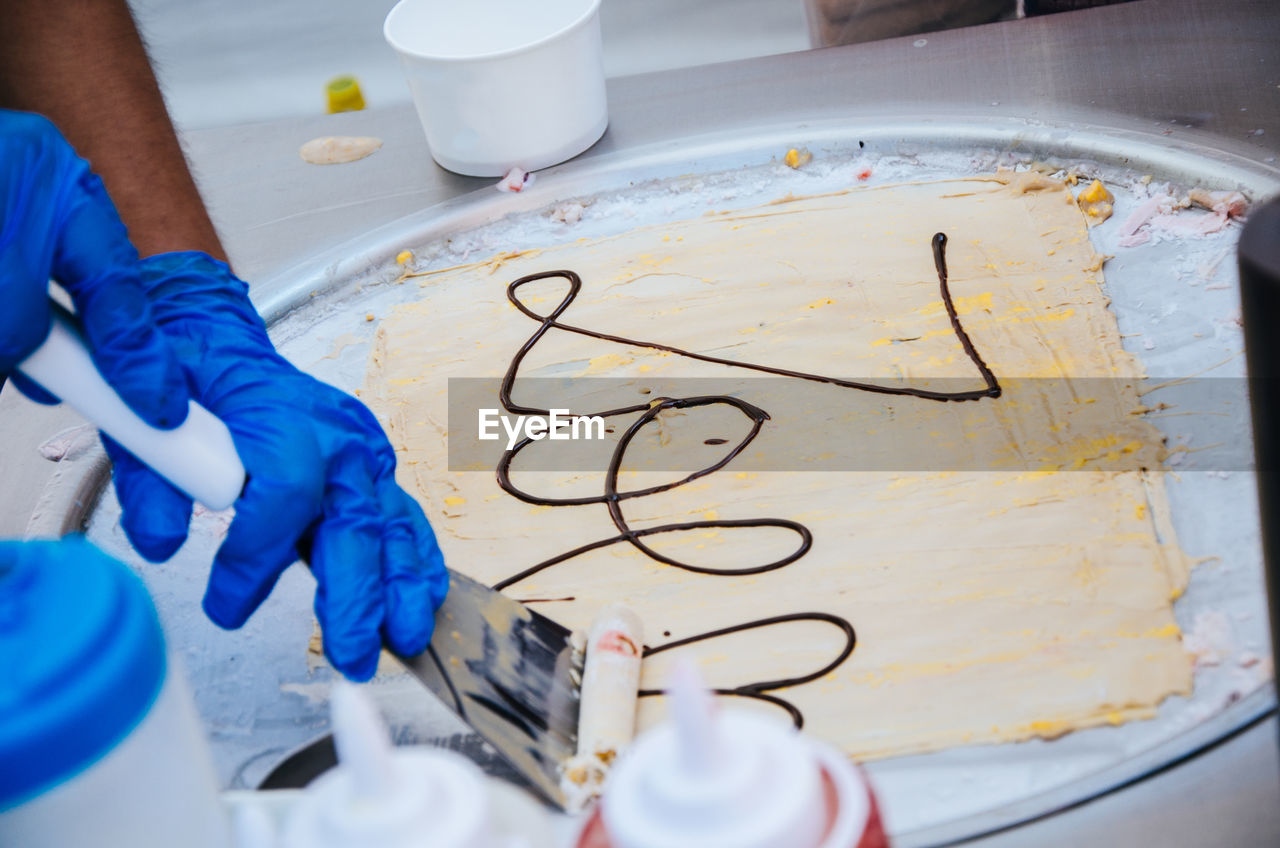 Cropped hand making ice cream on table