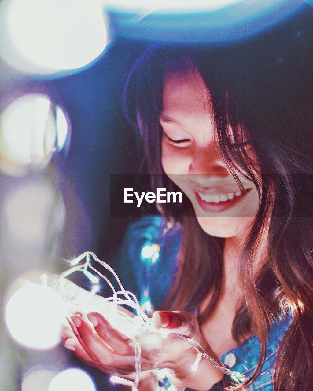 Close-up of happy young woman with illuminated string light