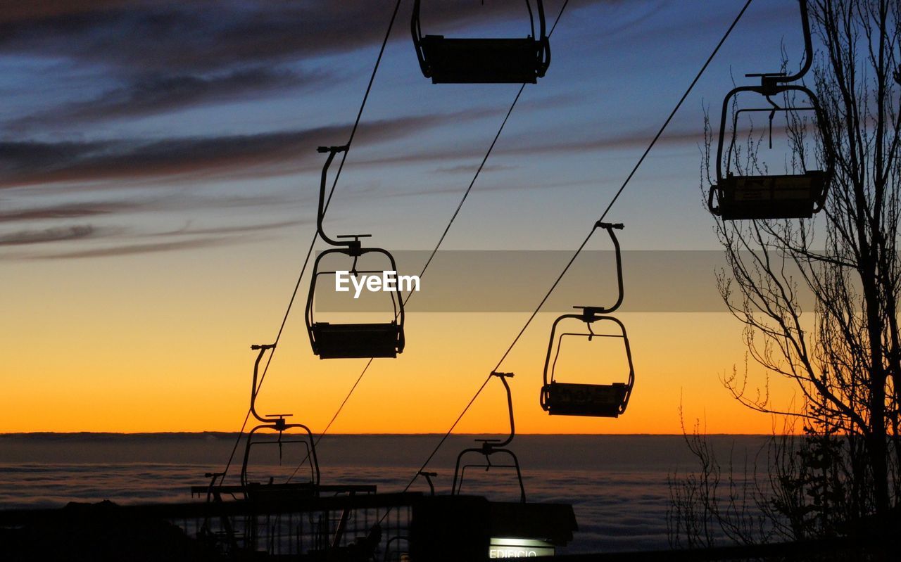 Silhouette ski lift against sky during sunset