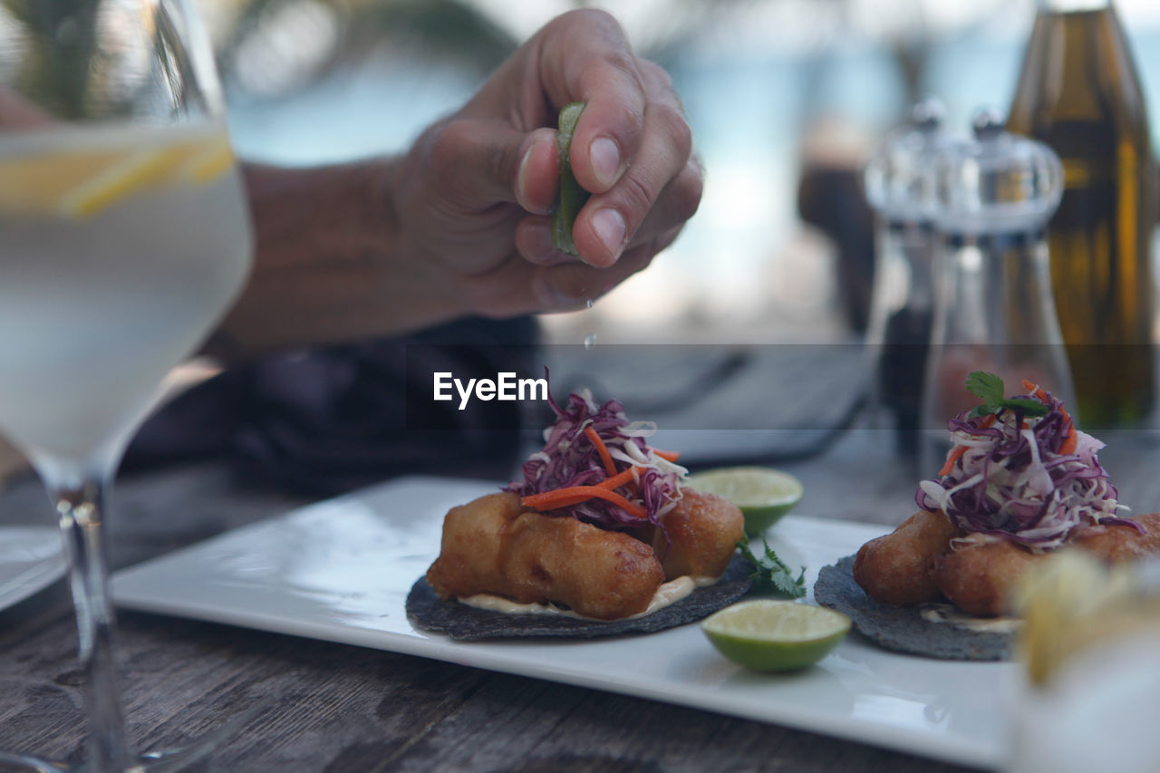 Close-up of hand squeezing lemon on table