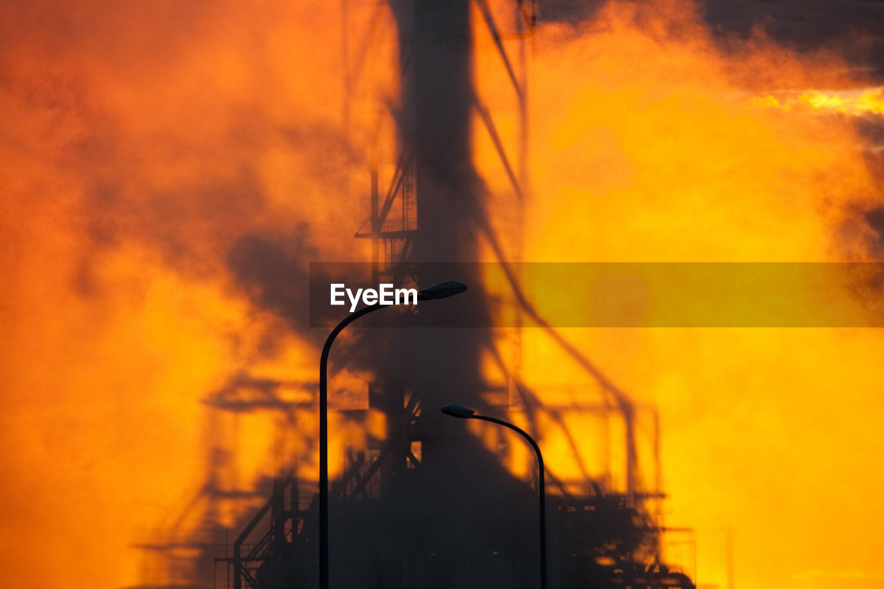 Smoke emitting from industrial building during sunset