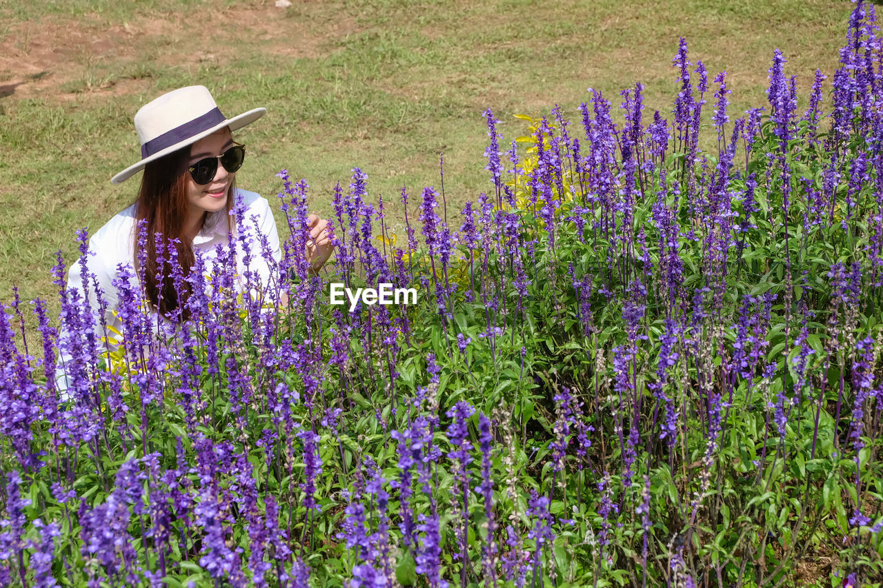 High angle view of smiling beautiful woman touching flowers