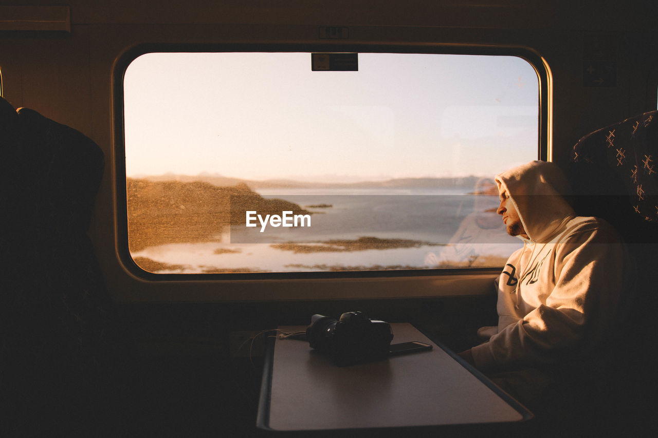 REAR VIEW OF BOY LOOKING THROUGH WINDOW