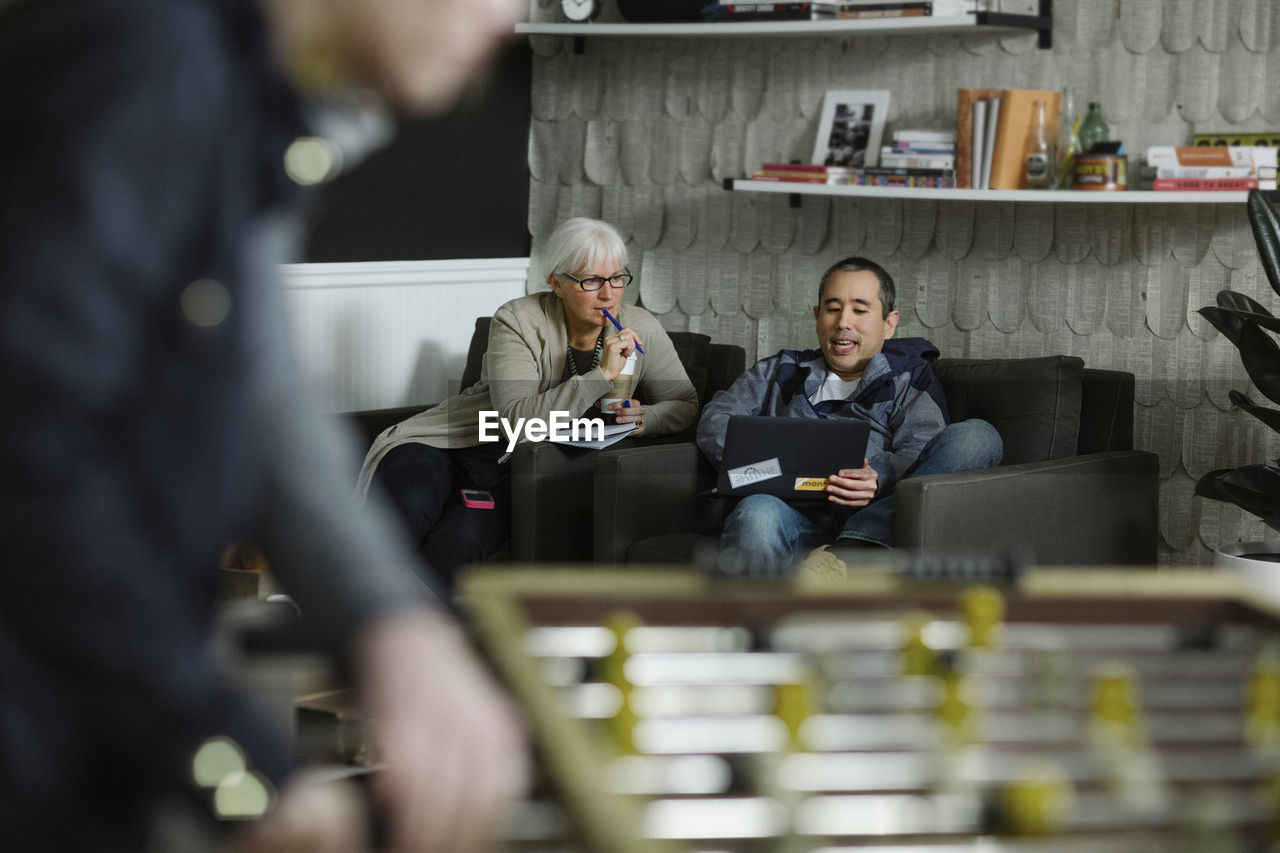 Business people discussing while sitting on sofa at office