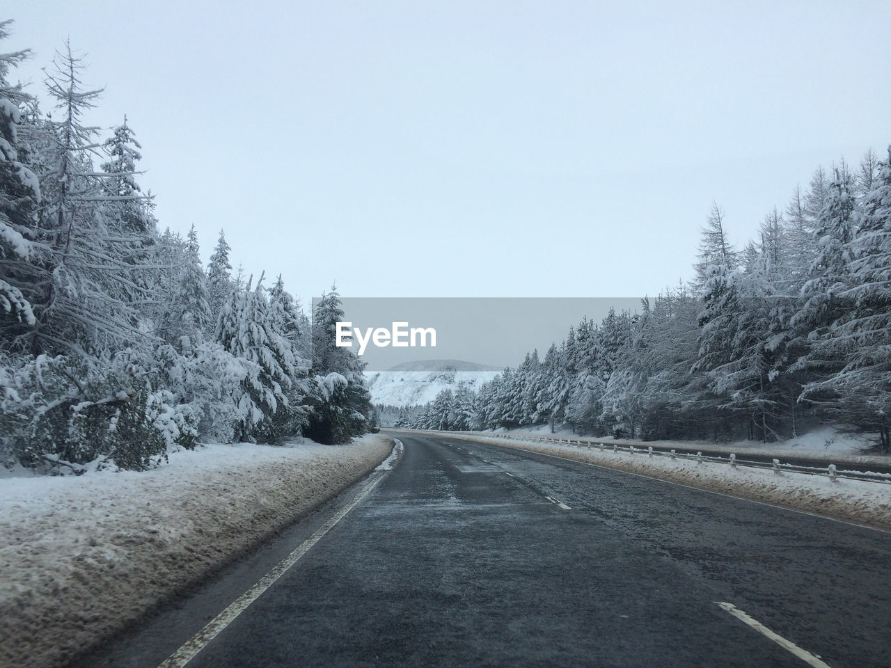 Road passing along snow covered forest