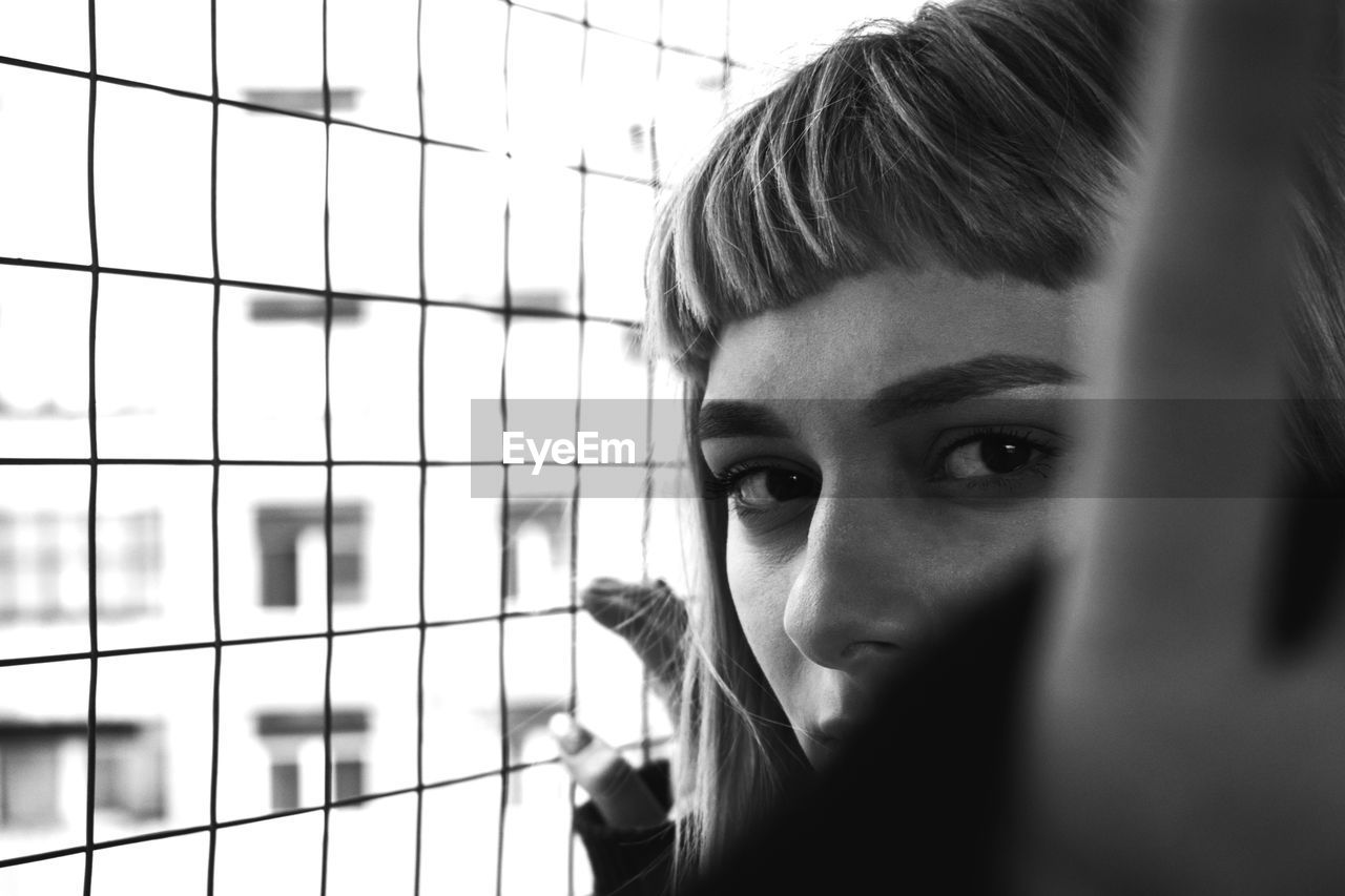 Close-up portrait of woman by window