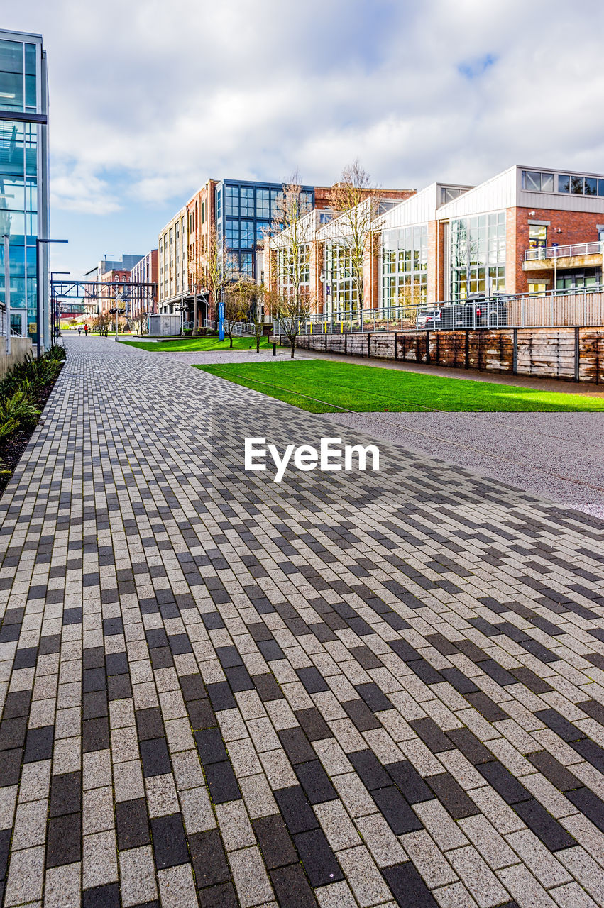 FOOTPATH AMIDST BUILDINGS AGAINST SKY