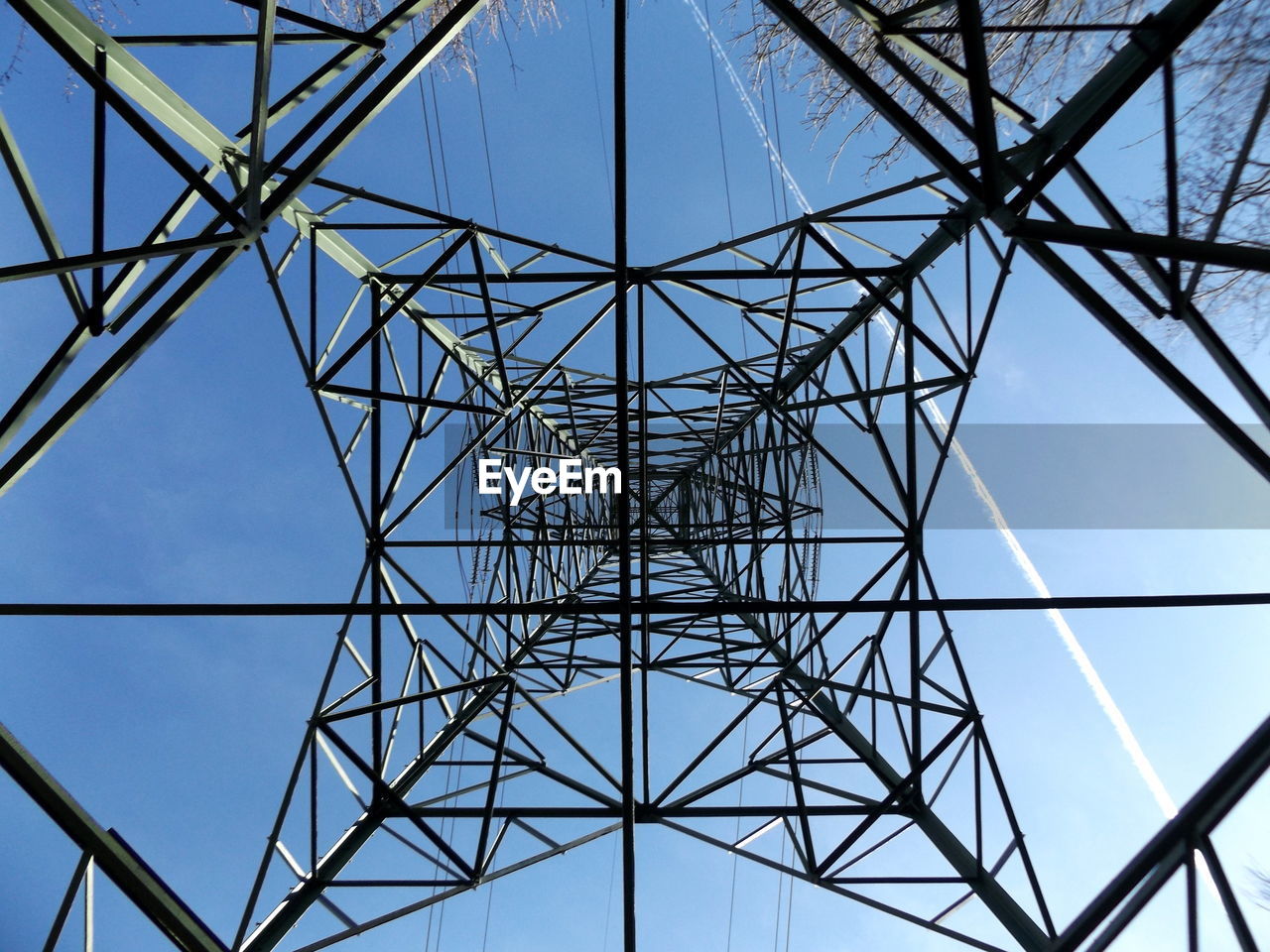 Low angle view of electricity pylon against clear blue sky