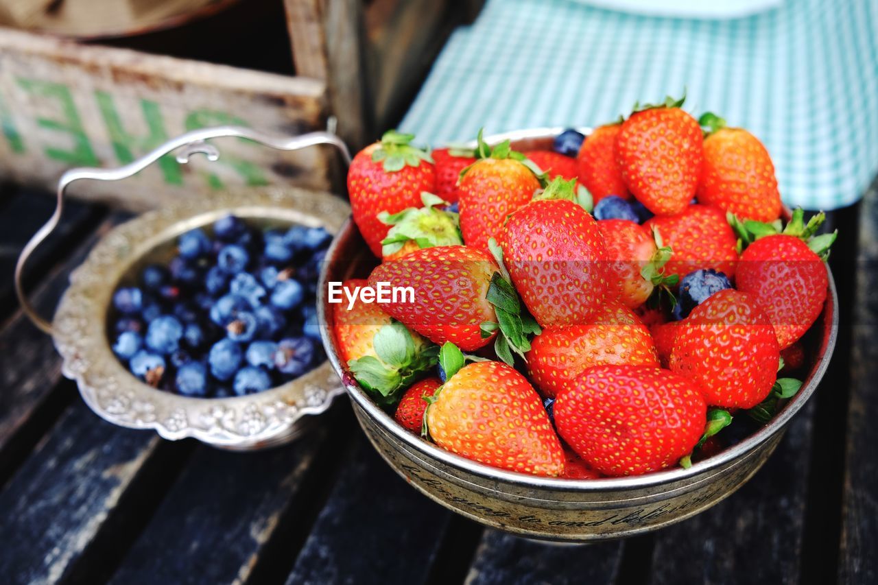 High angle view of strawberries and blueberries in containers on table