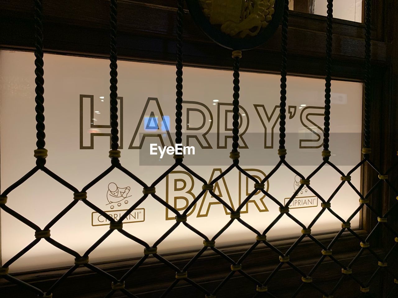 TEXT ON CHAINLINK FENCE AGAINST BUILDING SEEN THROUGH METAL GRATE