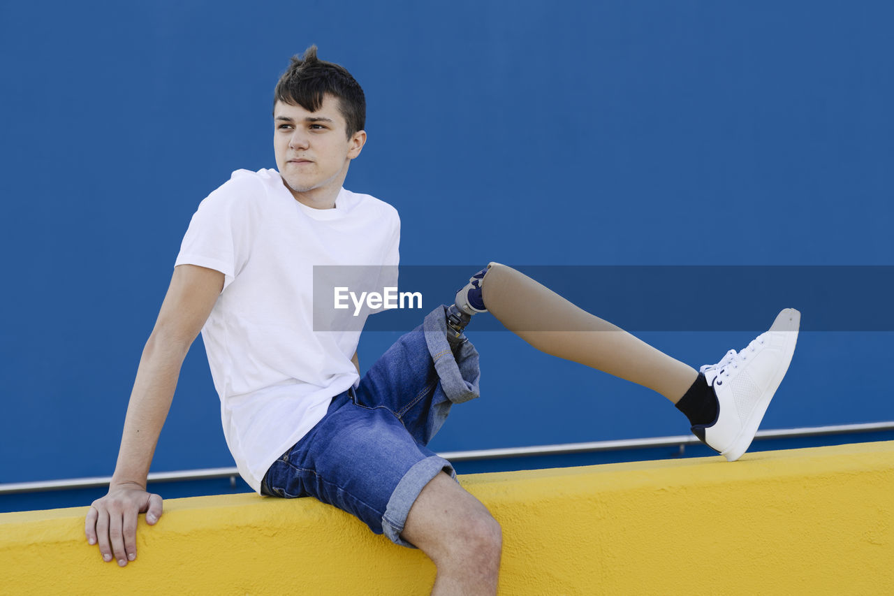 Handicapped teenager sitting on fence