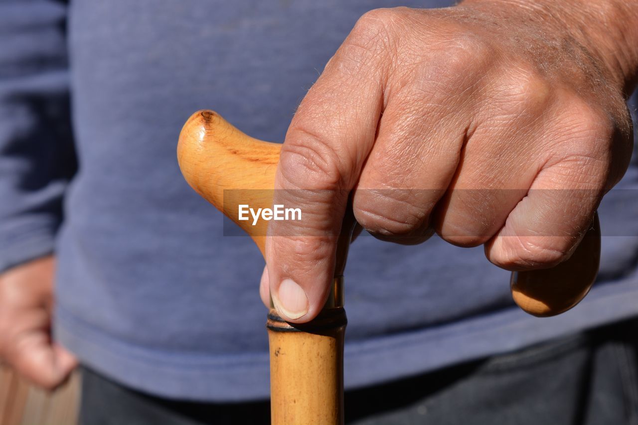 Close-up of man holding walking cane