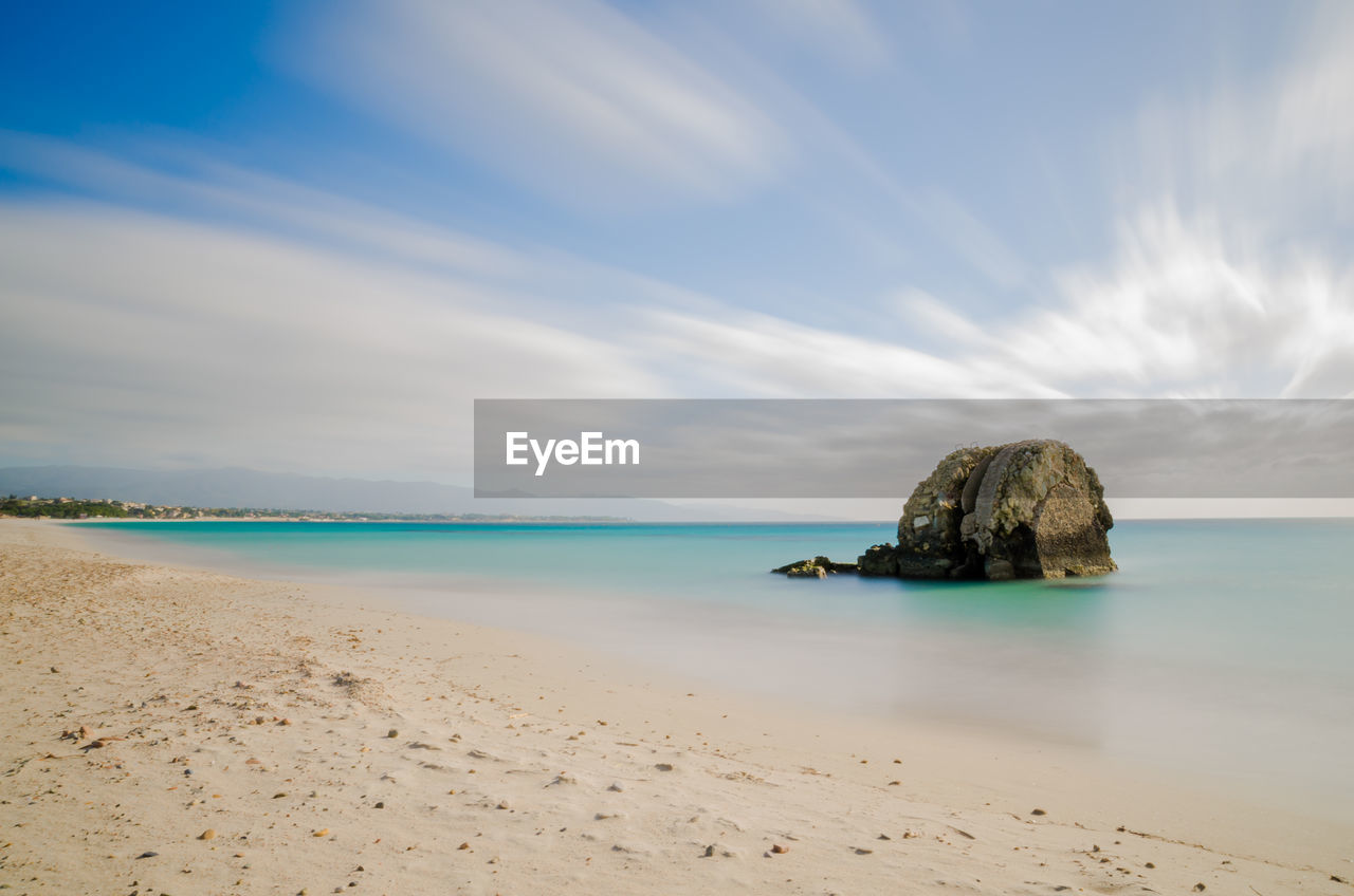 Scenic view of beach against cloudy sky