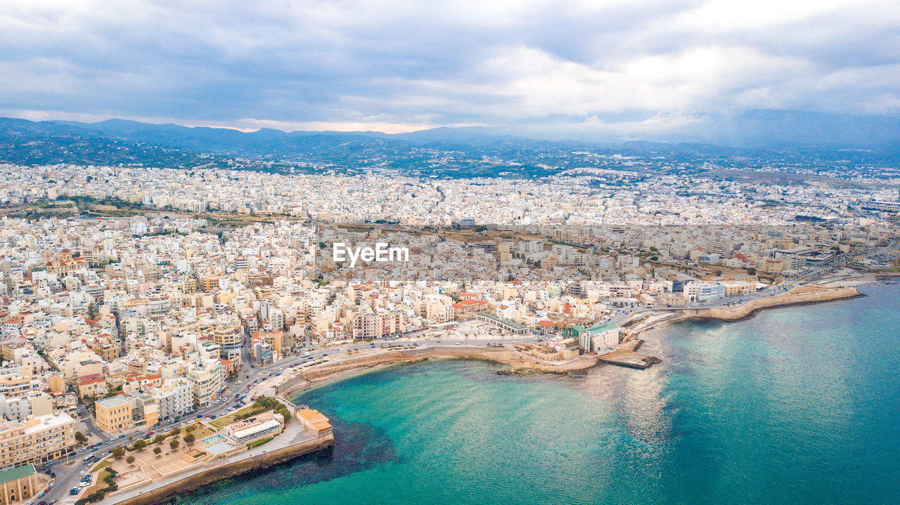 HIGH ANGLE VIEW OF TOWNSCAPE AGAINST SEA