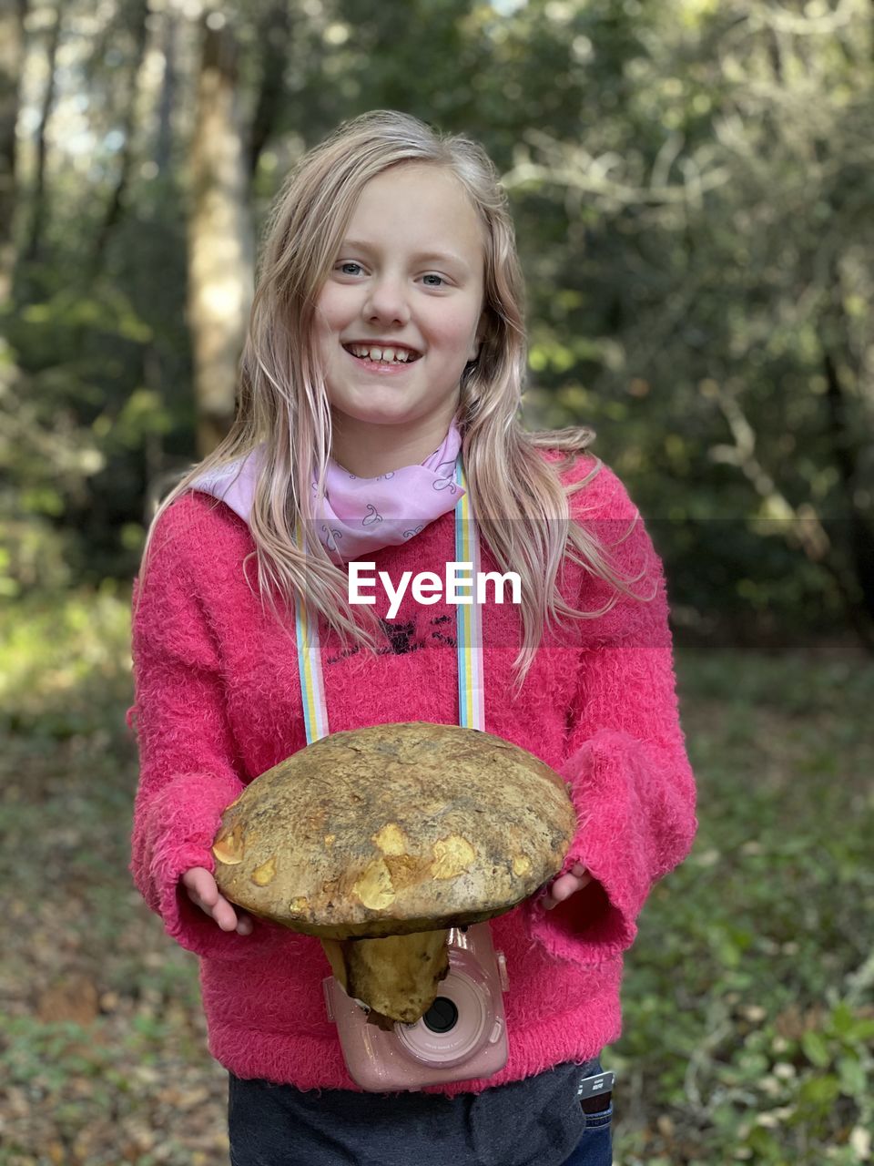 Portrait of smiling girl holding mushroom outdoors