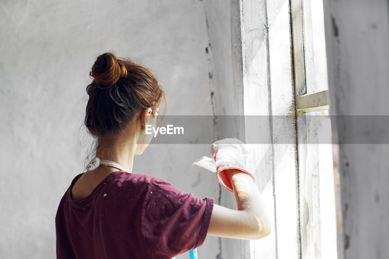 Rear view of woman standing against wall