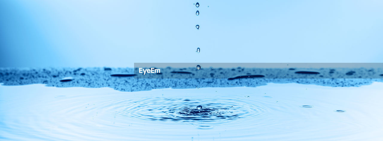 CLOSE-UP OF WATER SPLASHING AGAINST BLUE SKY AND CLOUDS