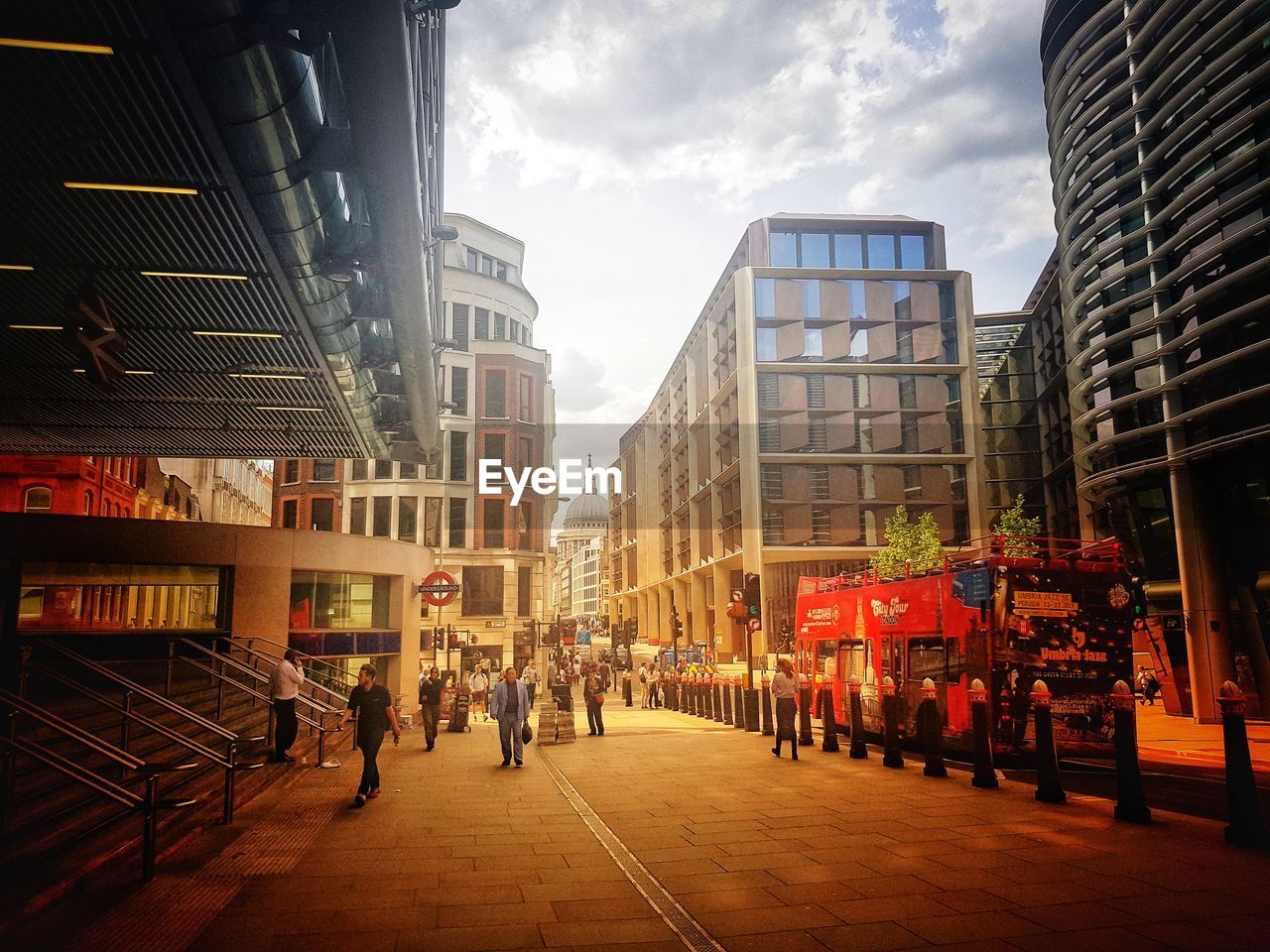 PEOPLE WALKING ON CITY STREET AMIDST BUILDINGS AGAINST SKY