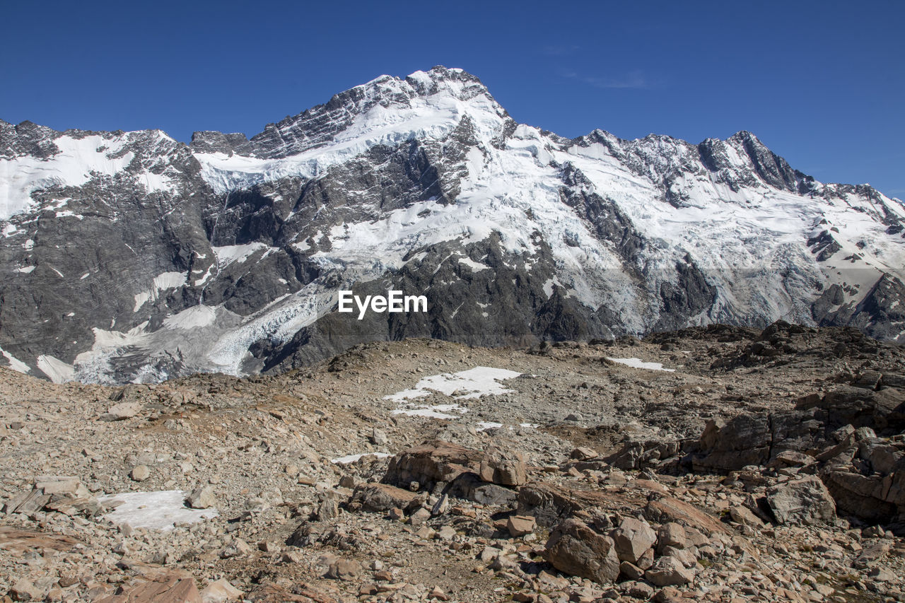 mountain, snow, cold temperature, winter, environment, scenics - nature, sky, landscape, mountain range, beauty in nature, nature, snowcapped mountain, ridge, moraine, clear sky, no people, adventure, ice, outdoors, travel destinations, mountain peak, rock, blue, day, activity, plateau, travel, land, summit, sports, mountain pass, leisure activity, sunny, tranquility, extreme terrain, cirque, tranquil scene