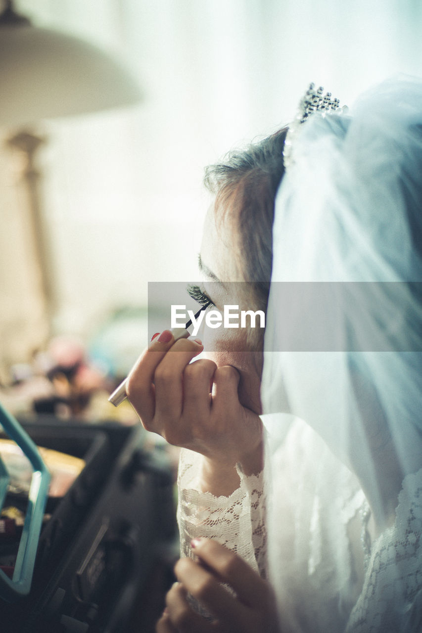 Bride applying make-up while sitting at home