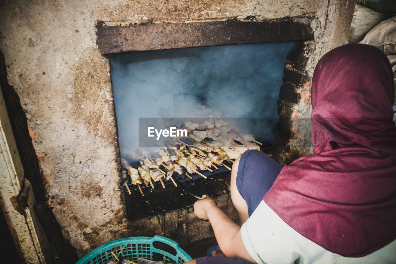 Woman preparing meat in barbecue grill