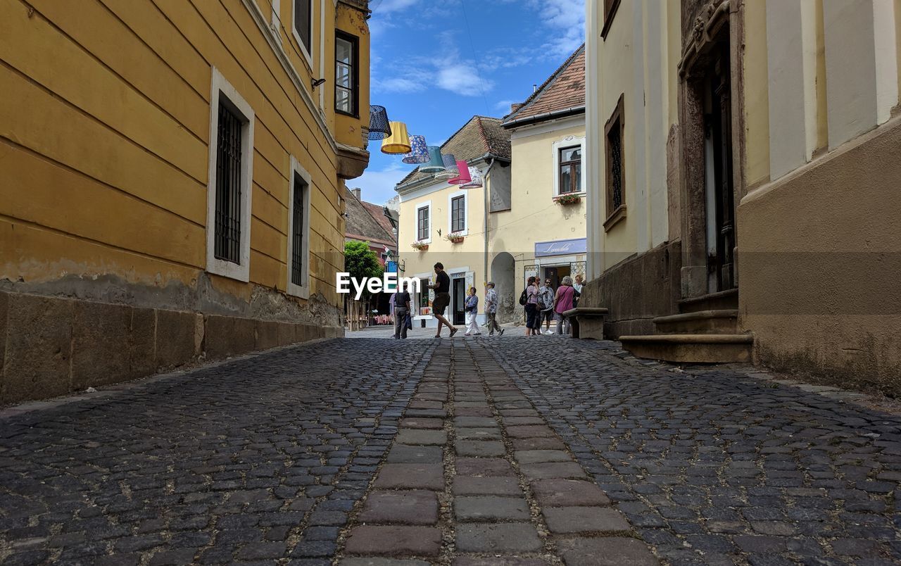 PEOPLE WALKING ON FOOTPATH AMIDST BUILDINGS