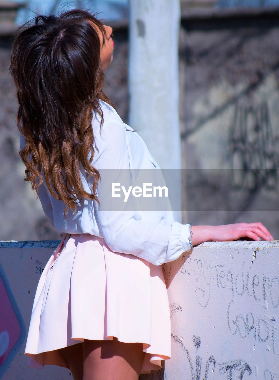 Rear view of fashionable woman standing by against wall