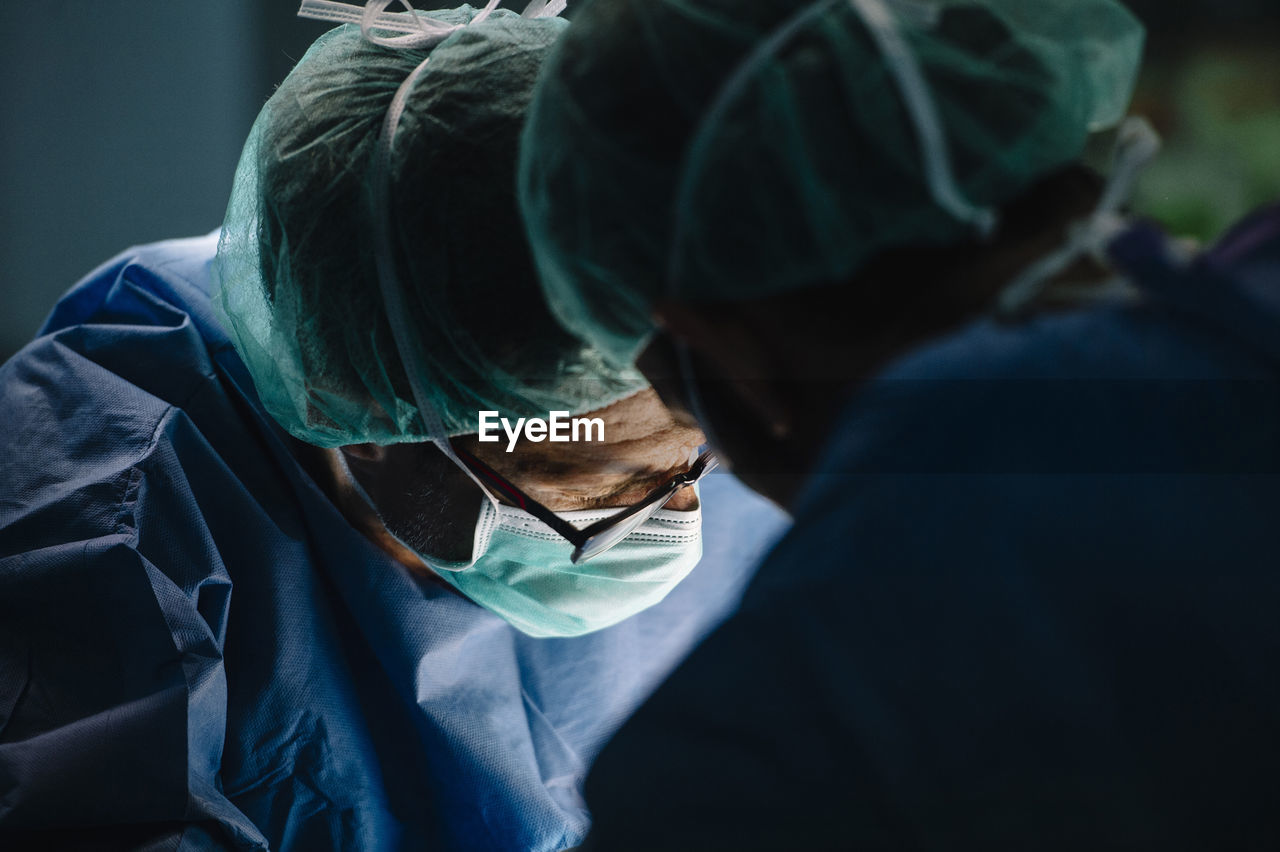 Male orthopedic surgeon with coworker operating surgery in emergency room