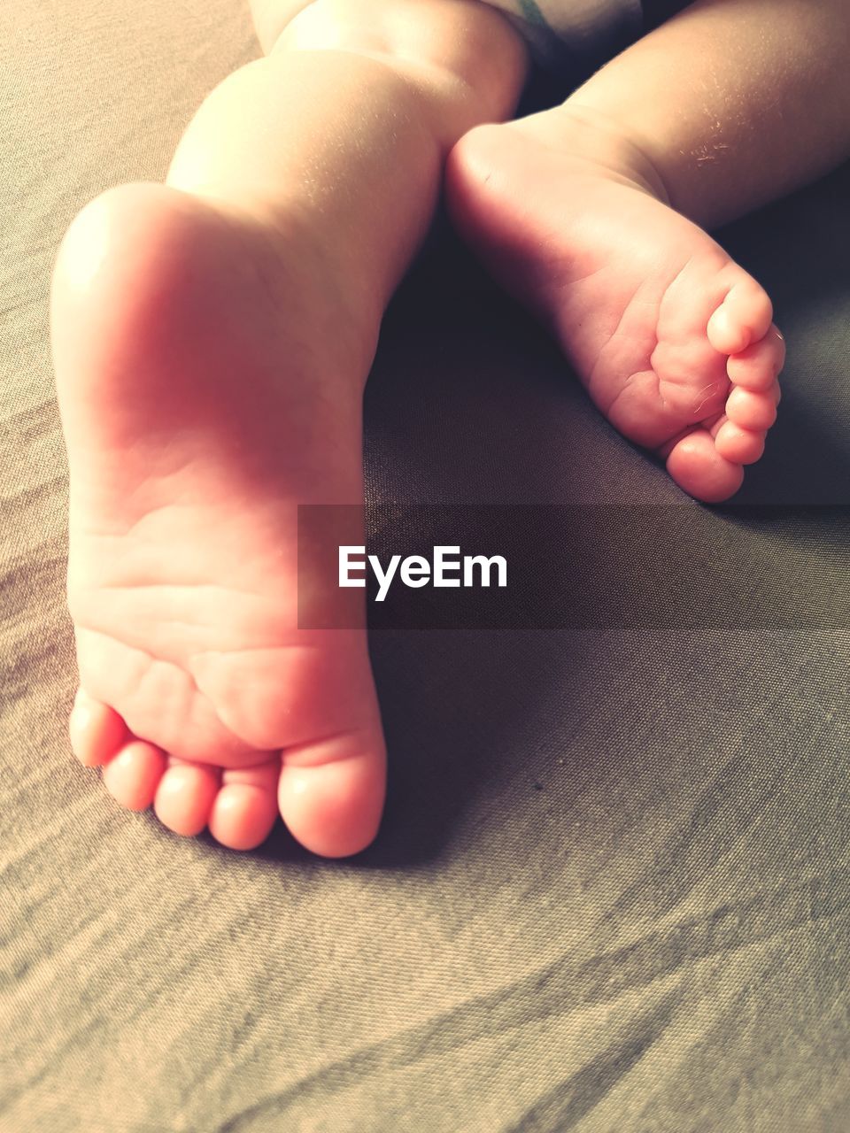 CLOSE-UP OF BABY FEET ON BED