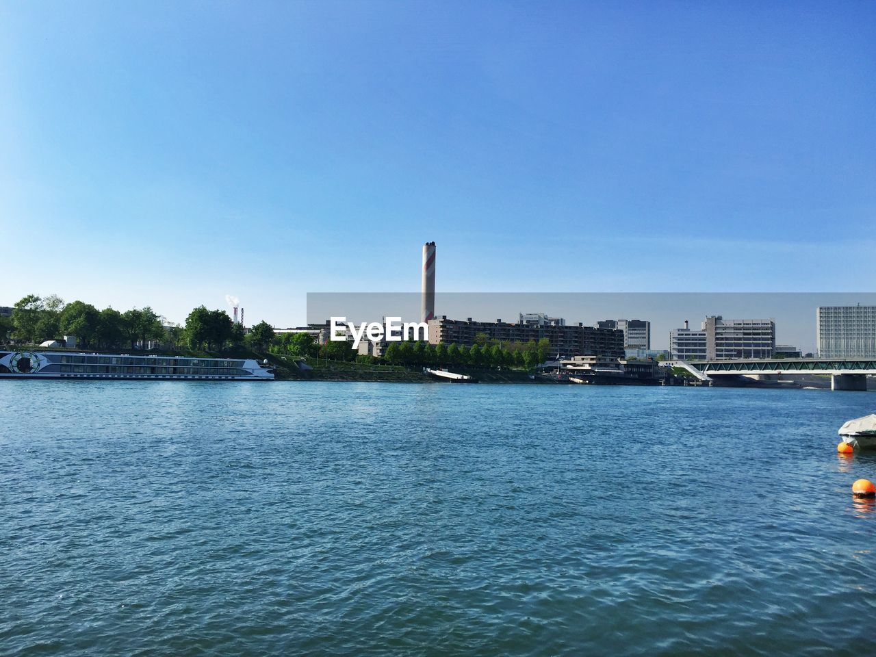 Scenic view of rhine river by buildings against clear blue sky