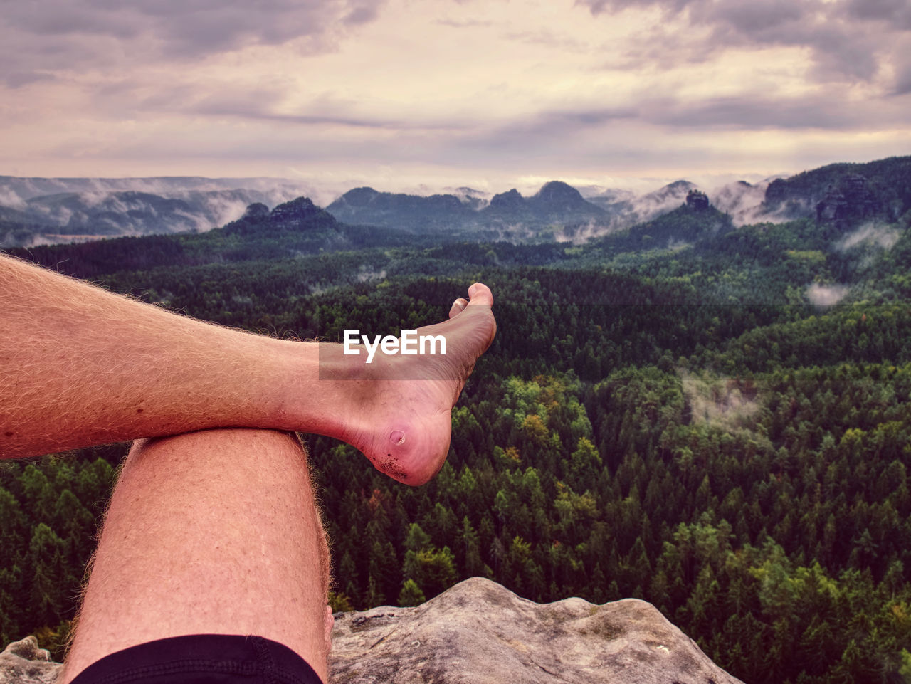 First person perspective shot from hiker sit at edge of cliff above rain forest valley. feel freedom