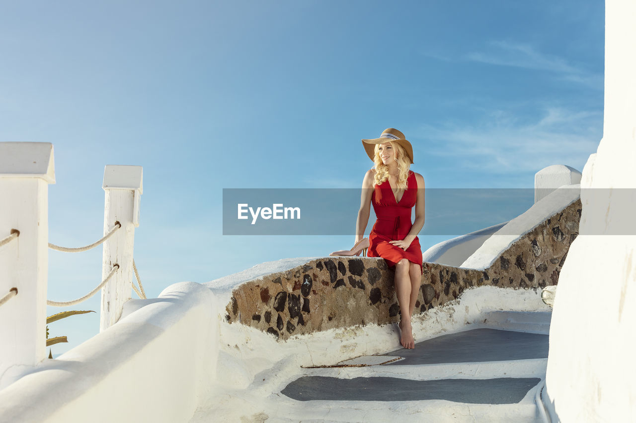 Low angle view of woman looking away while sitting against sky