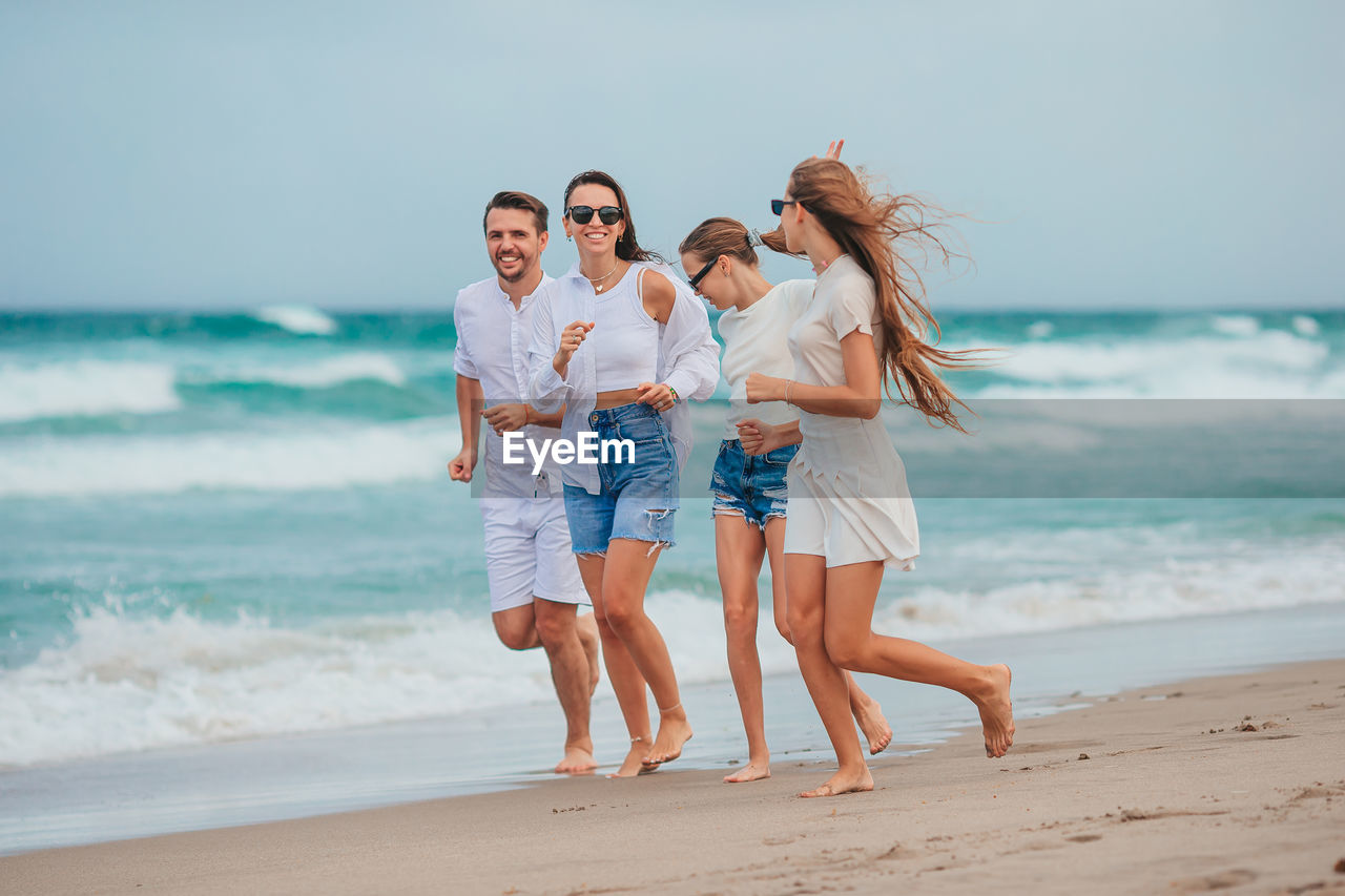 smiling friends standing at beach