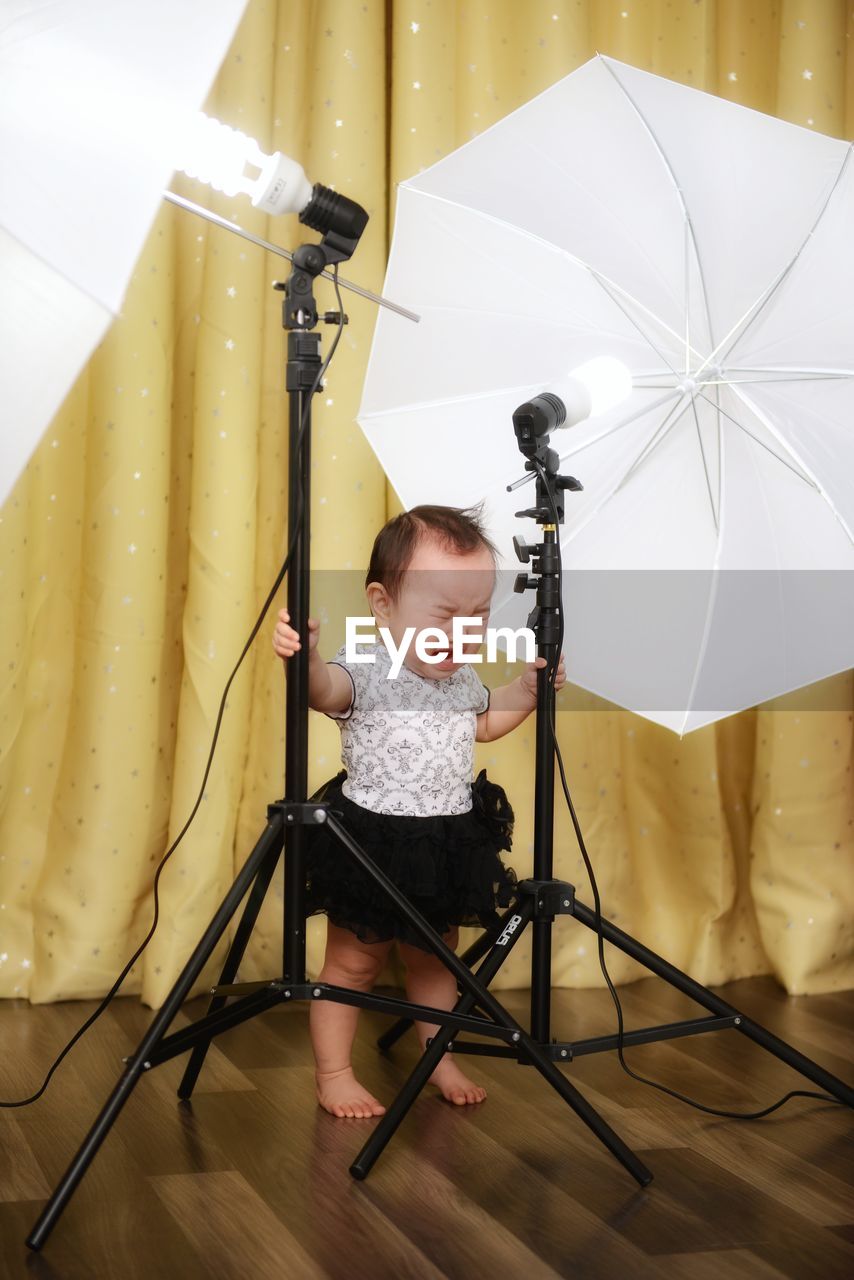Full length of baby girl crying while standing in photo studio