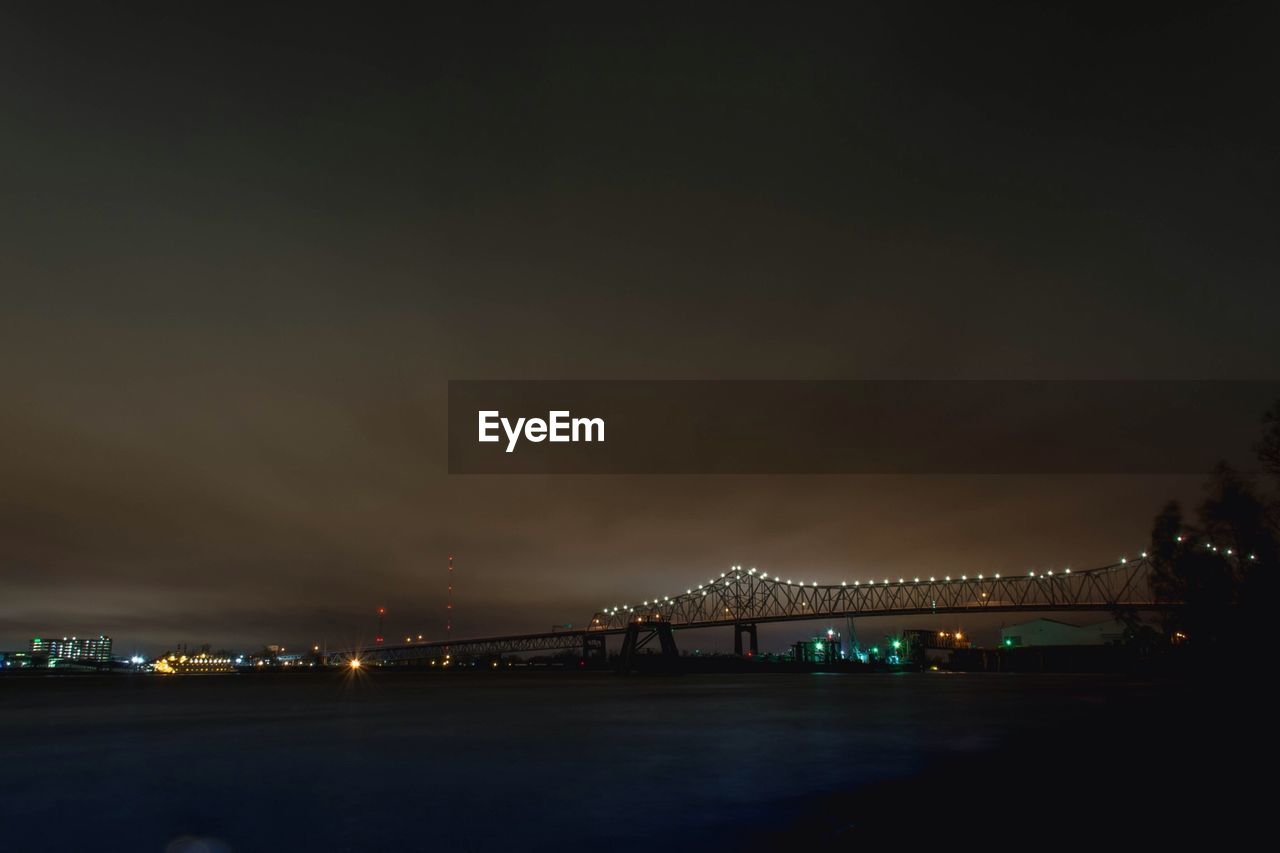 SUSPENSION BRIDGE OVER RIVER AT NIGHT