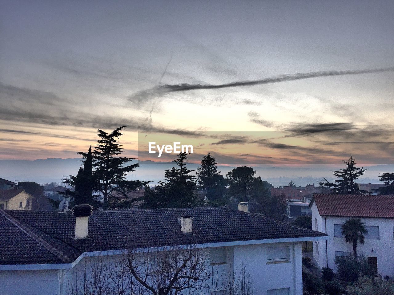 Houses in city against sky during sunset