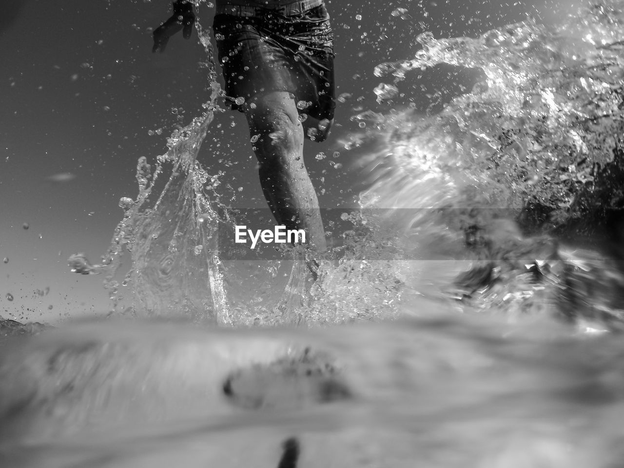 Midsection of man splashing water in sea