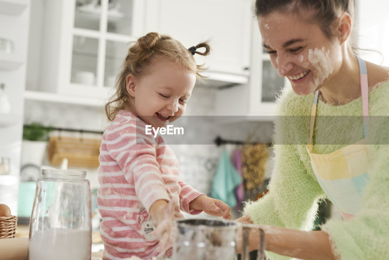 Mother and daughter preparing food in kitchen at home