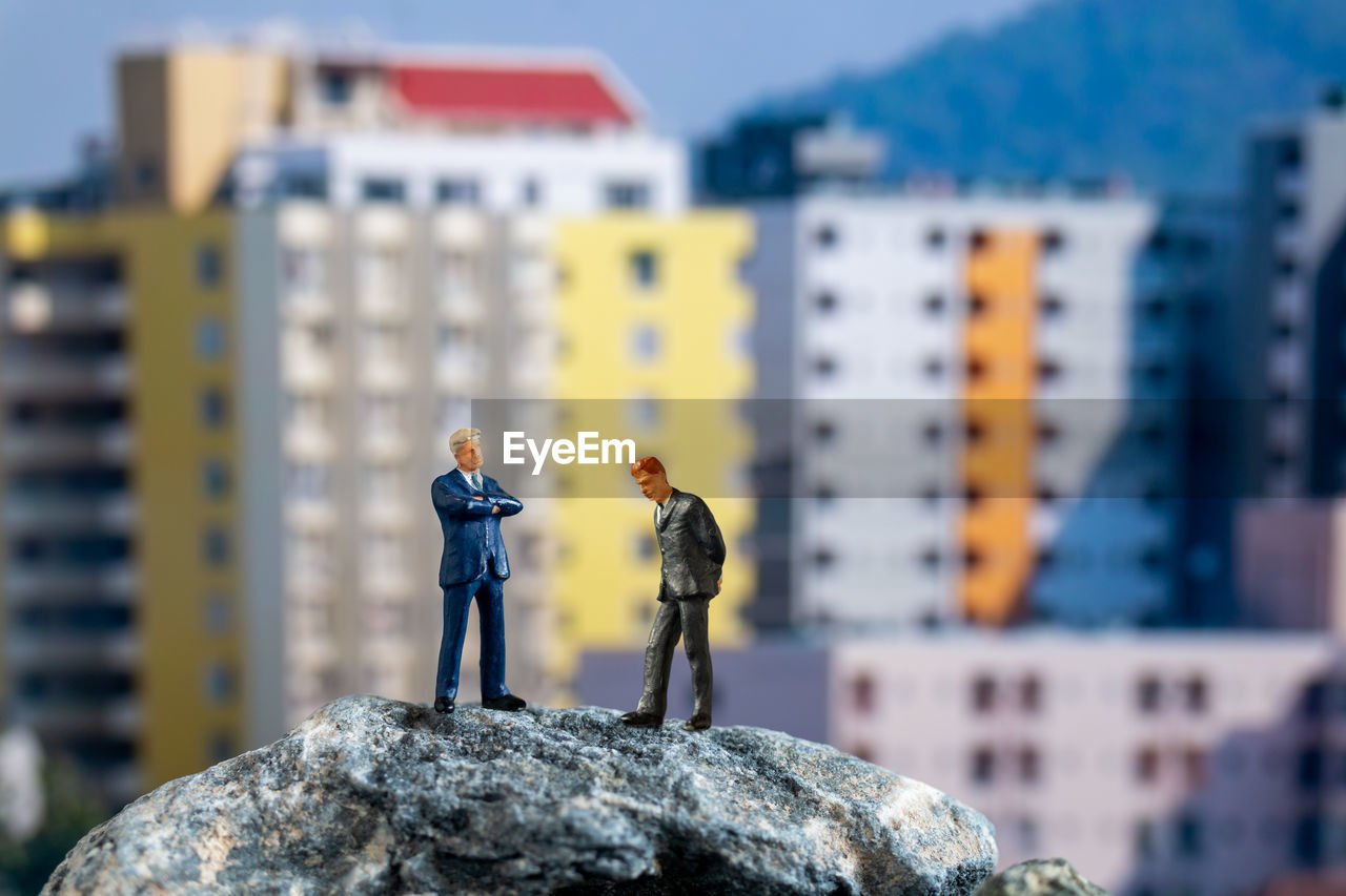 MAN STANDING ON ROCK AGAINST BLURRED BACKGROUND