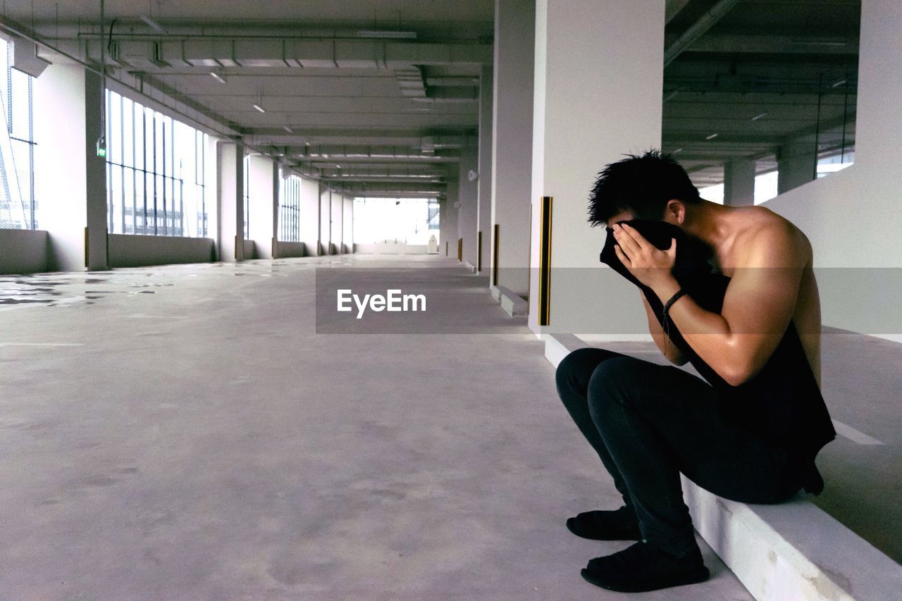 Side view of man covering his face with t-shirt